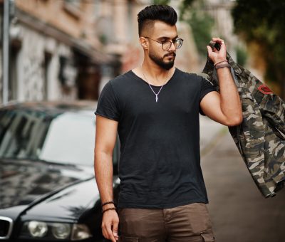 Awesome beautiful tall ararbian beard macho man in glasses and black t-shirt walking against business car.